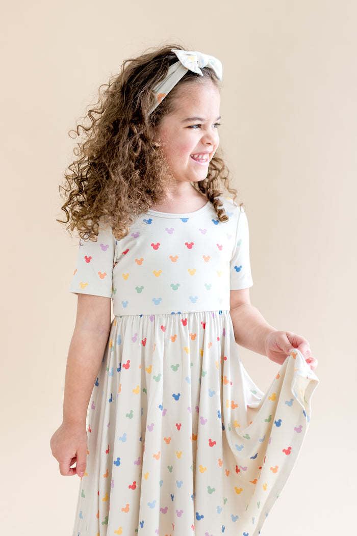 Girl in a twirl dress with colorful mickey mouse head pattern