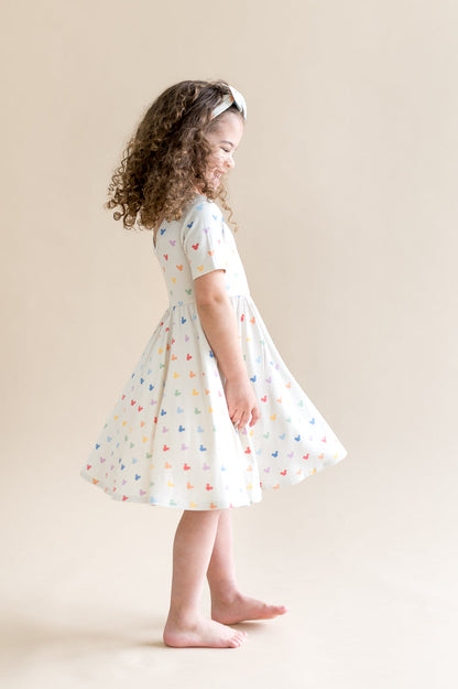 Girl twirling in a dress with  colorful mickey mouse head pattern