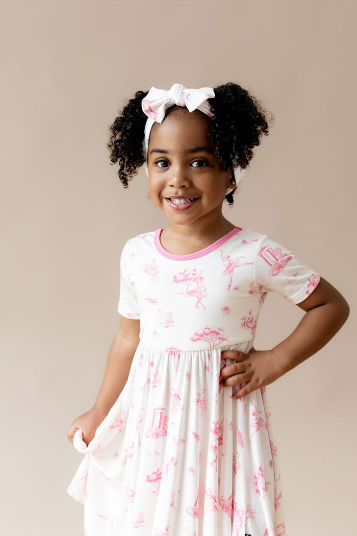 Close up of young girl wearing the Twirl Dress in Toile Ballet with matching bow