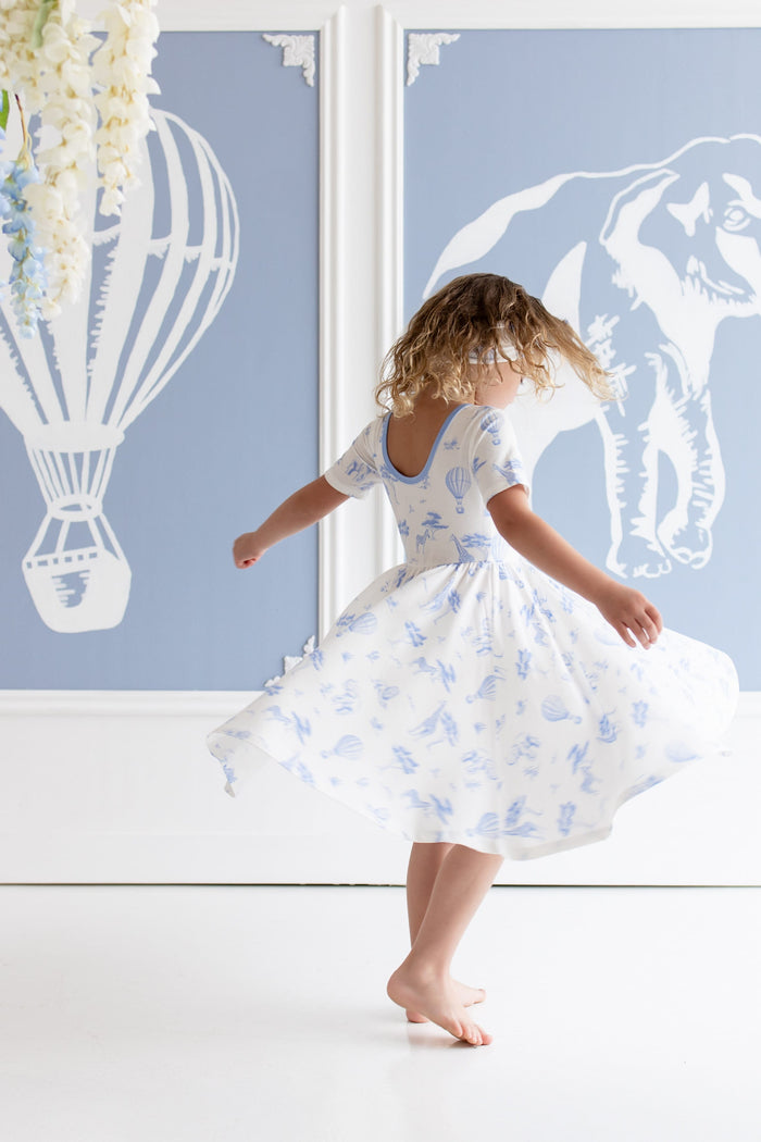 Young girl twirling in the Twirl Dress in Toile Safar showing the ballerina back line