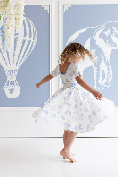 Young girl twirling in the Twirl Dress in Toile Safar showing the ballerina back line