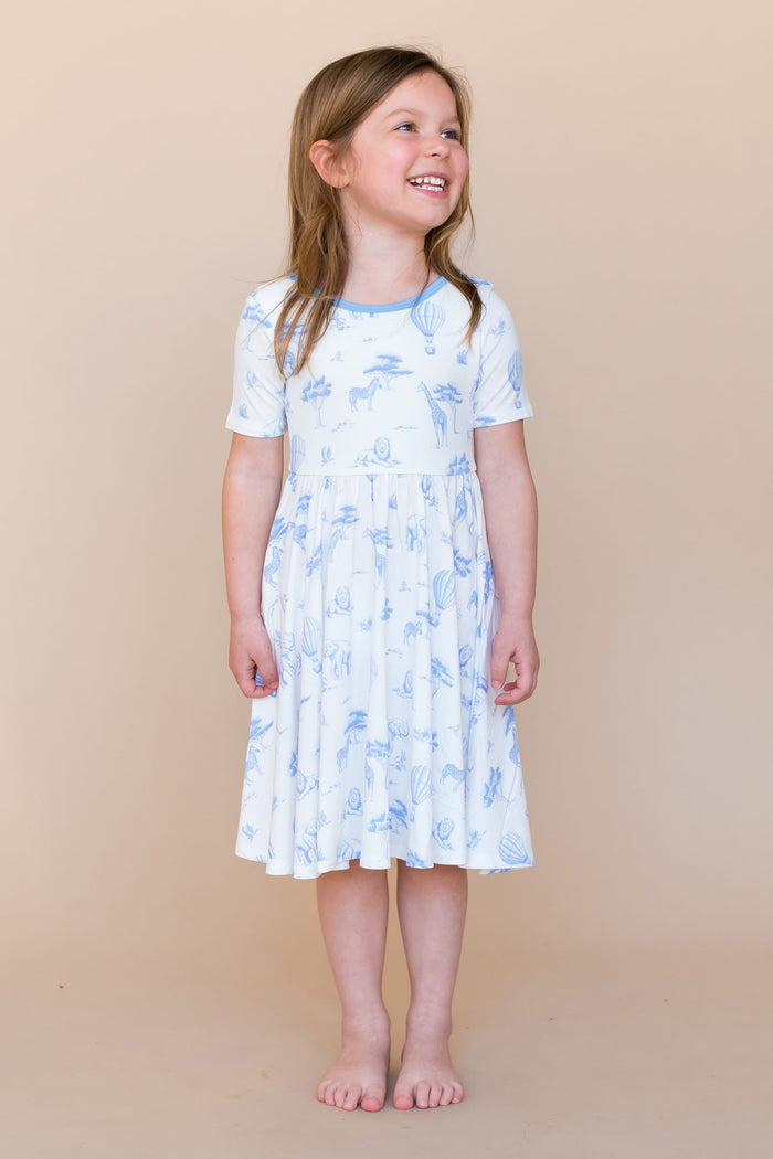 Young smiling girl modeling the Twirl Dress in Toile Safari