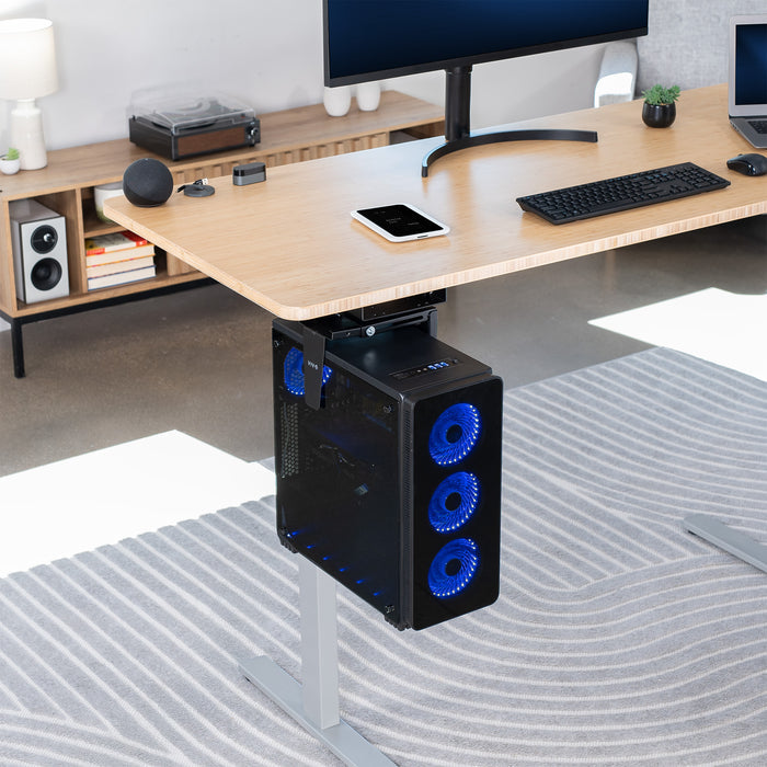 Computer setup with a desk, monitor, keyboard, and a black computer PC with blue LED lights in an under-desk PC mount.