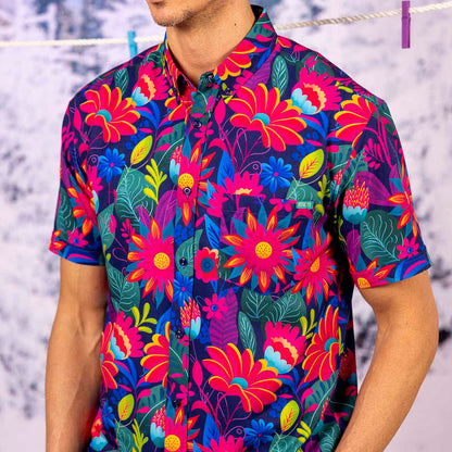 Person wearing a colorful Untamed Tropic – KUNUFLEX Short Sleeve Shirt with a blurred snowy background