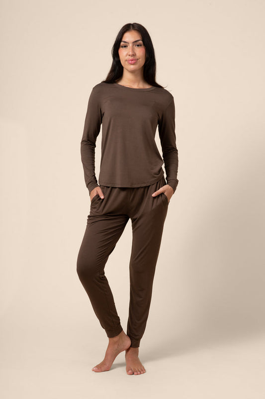 Woman wearing a brown long-sleeve top and pants on a beige background