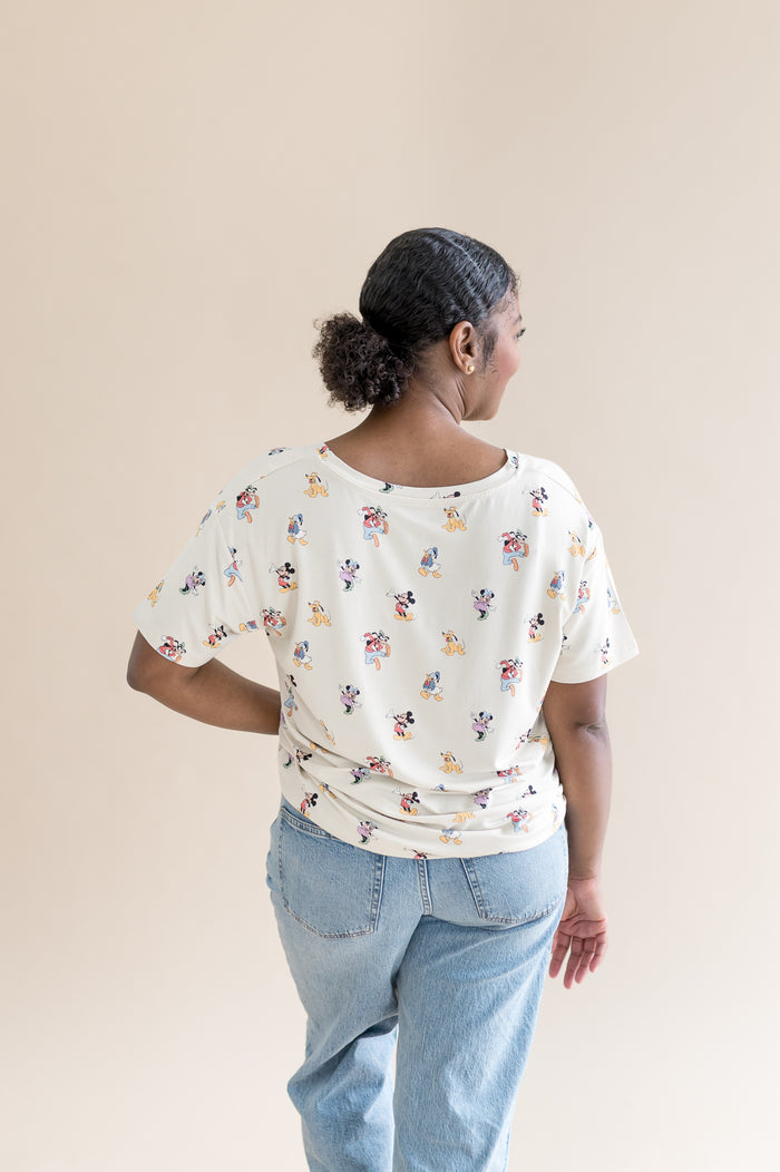 Woman showing the back of the oversized v-neck tshirt that features a pattern of mickey mouse and friends