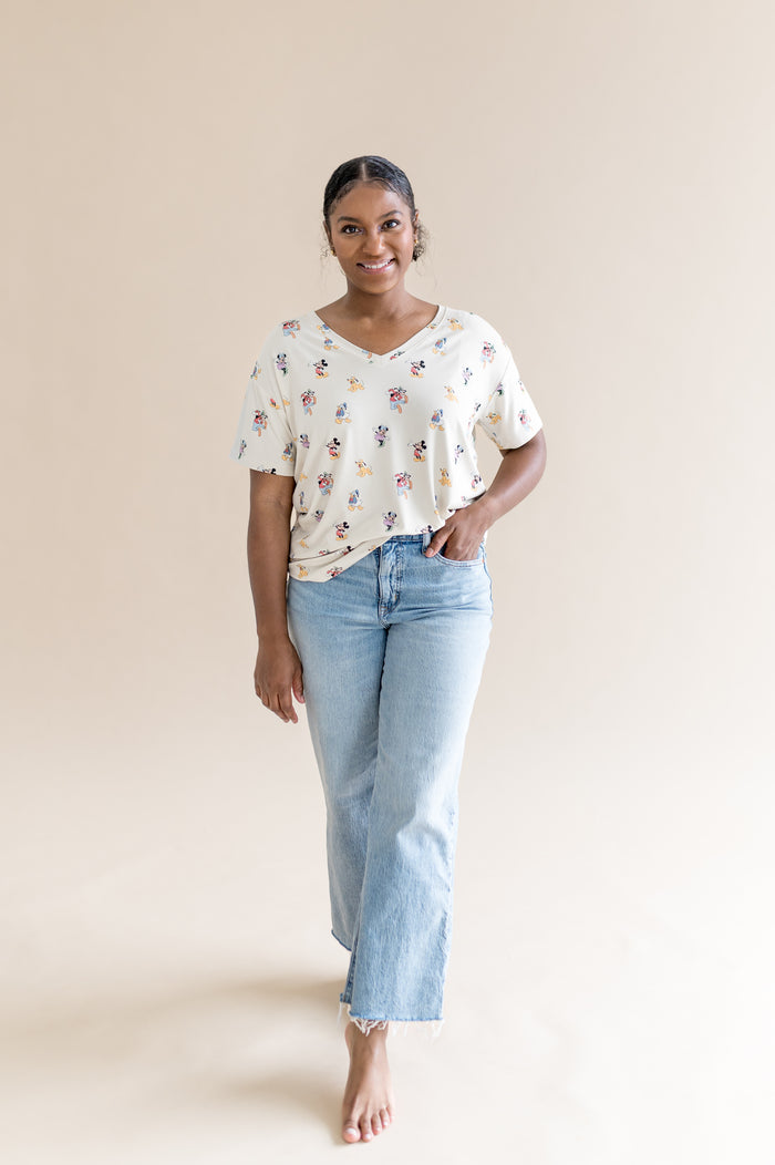 Woman wearing oversized v-neck tshirt that features a pattern of mickey mouse and friends and jeans