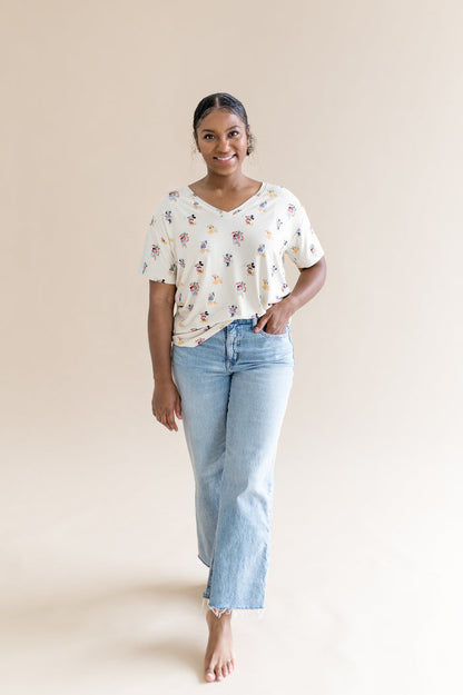 Woman wearing oversized v-neck tshirt that features a pattern of mickey mouse and friends and jeans