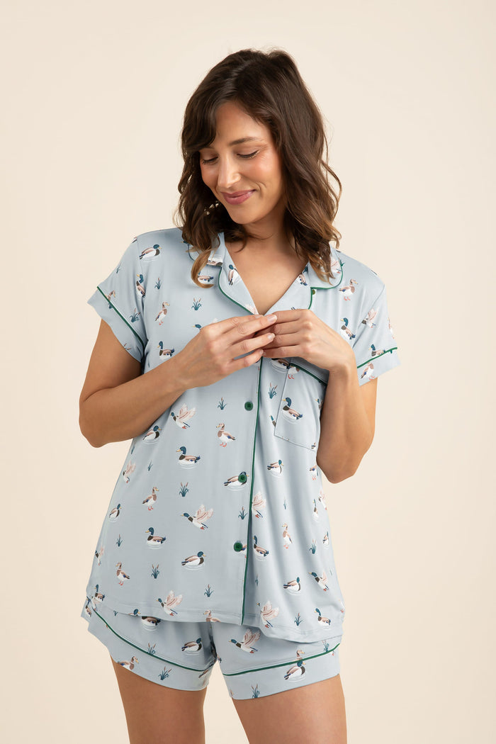 Woman wearing a light blue pajama set with duck print on a beige background