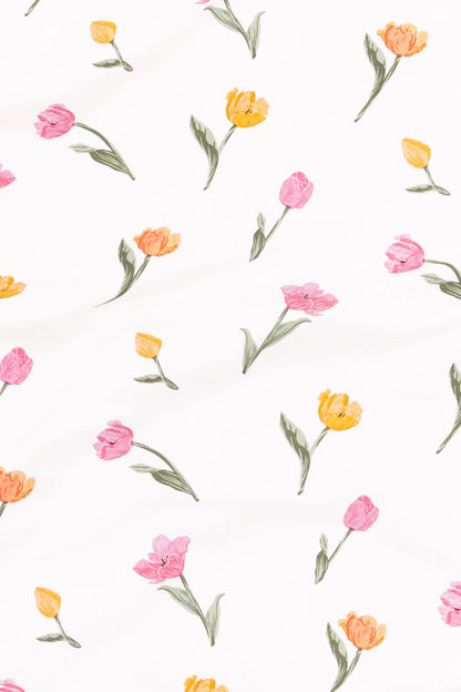 Close up of the fabric swatch of the print tulip showing the yellow, orange and pink tulips with green stems on a white background