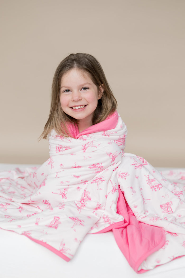 Young girl sitting with the Youth Blanket in Toile Ballet 1.0 wrapped around her