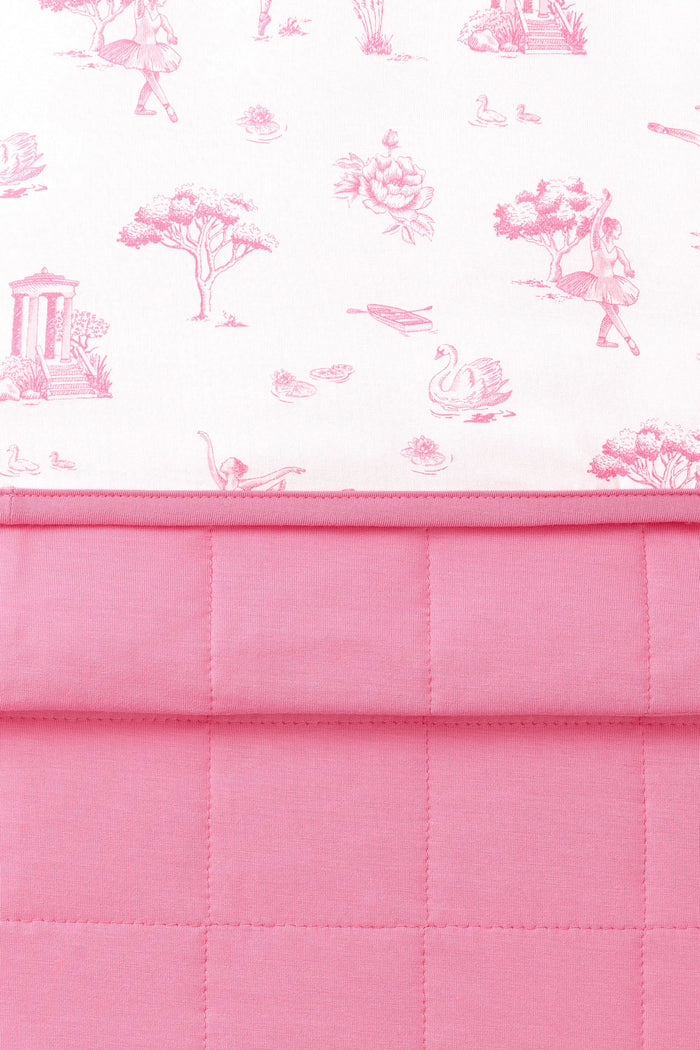 Close up of the Youth Blanket in Toile Ballet 1.0 showing the pink quilted backing and smooth printed top layer